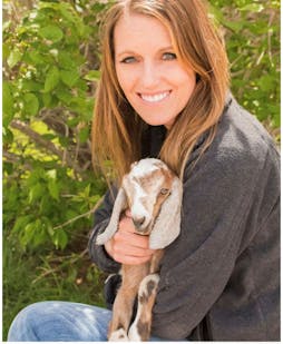 woman with strawberry blonde hair holding a goat with long floppy ears