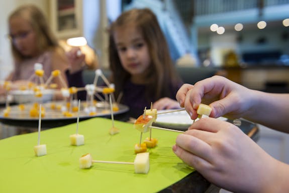 Children building with marshmallows, toothpicks, and cheese cubes